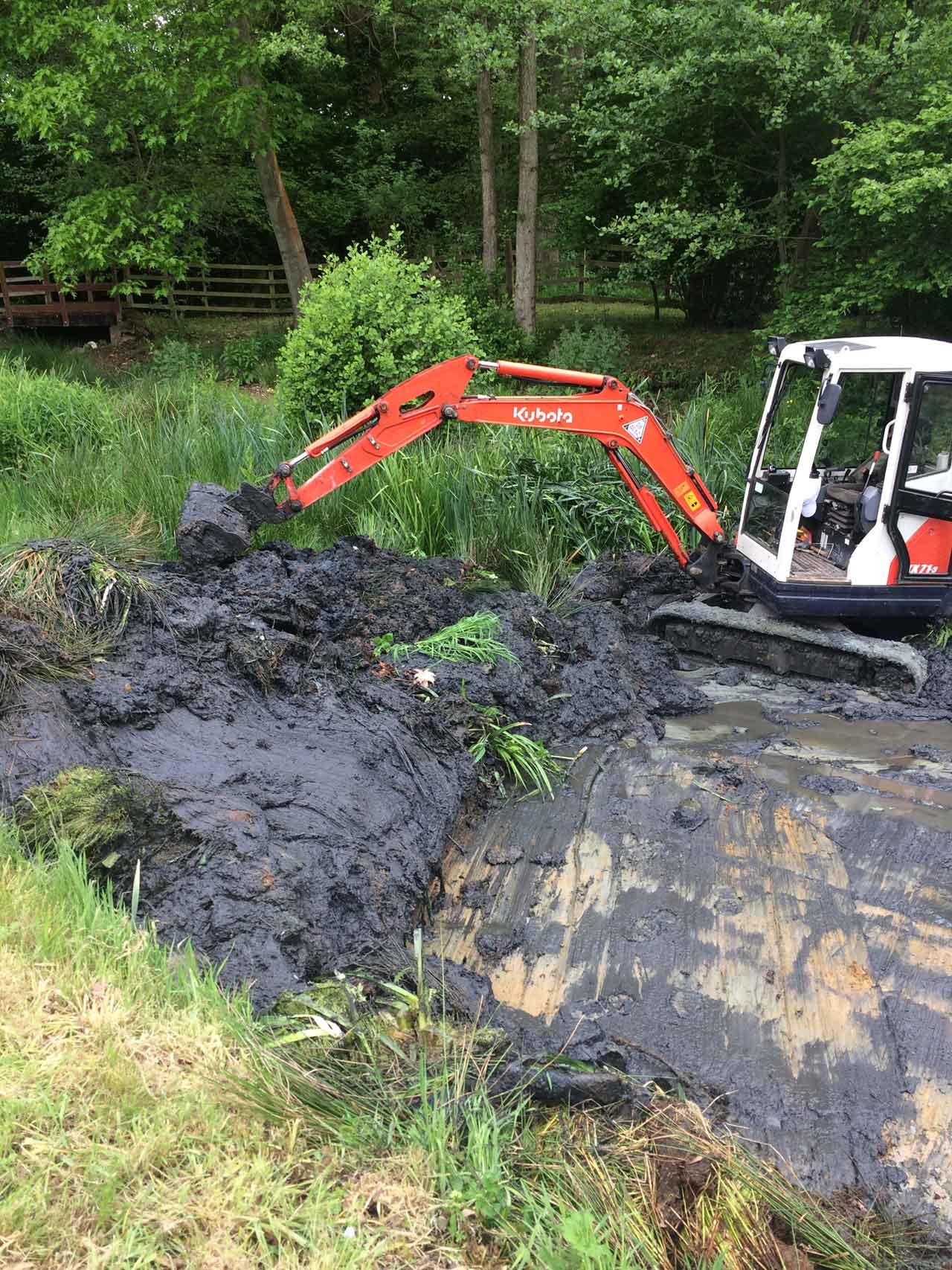 Image of a Kubota excavator clearing a lake ready for traditional clay lake relining at Barkham in Berkshire - Let the digger do it!