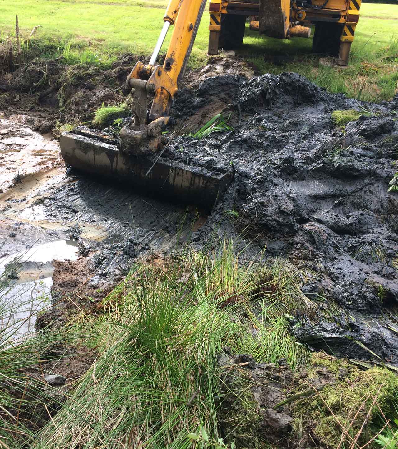 Image of a JCB cleaning the edge of a lake at Barkham in Berkshire - Lake dredging, lake cleaning and traditional clay lake lining at Barkham Manor in Berkshire - Let the digger do it!